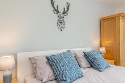 a bedroom with a bed with blue pillows and a deer skull on the wall at 1 Bed in Buxted oc-t32799 in Buxted