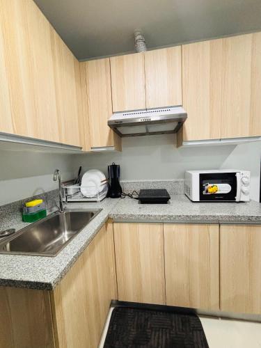 a kitchen with a sink and a microwave at Bright and Cozy Escape with Plush Touches in Mandurriao