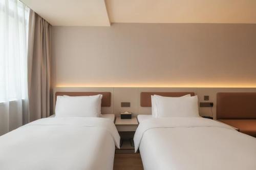 two beds sitting next to each other in a room at JINbang HOLIDAY HOTEL in Xiamen