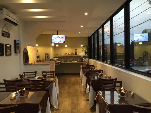 a dining room with tables and chairs and windows at Barueri Premiêr Hotel in Barueri