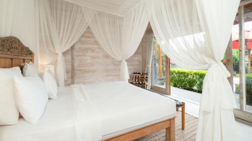 a bedroom with a white bed and a window at Villa Taramille by Villa Finder in Kerobokan