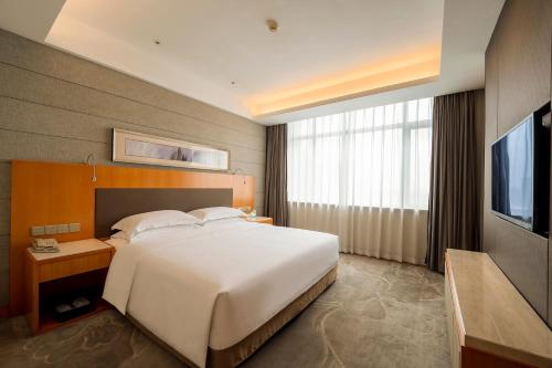 a bedroom with a large white bed and a television at Jinling Grand Hotel in Hefei