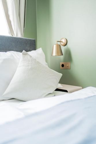a bed with white sheets and pillows and a lamp at HOME1 - Augarten City Stay Boutique Hostel in Vienna