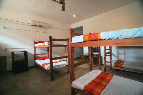a room with three bunk beds and a tv at Rise & Set Arugam bay in Arugam Bay