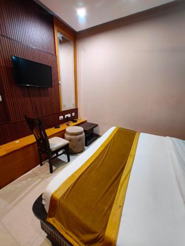 a bedroom with a bed and a chair and a tv at The royal hotel in Bareilly