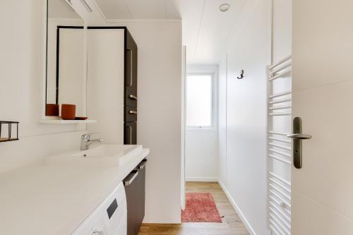 a white bathroom with a sink and a mirror at Séjour détente en famille à Bretignolles-sur-Mer in Brétignolles-sur-Mer