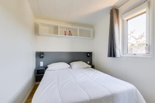 a white bed in a room with a window at Séjour détente en famille à Bretignolles-sur-Mer in Brétignolles-sur-Mer