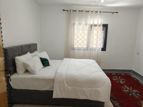 a bedroom with a white bed with a window at Apartement khadija in Azrou