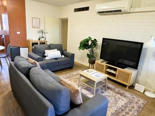 Una sala de estar con sofás y un televisor de pantalla plana. en Stylish 3 Bedroom Apartment, en South Hedland