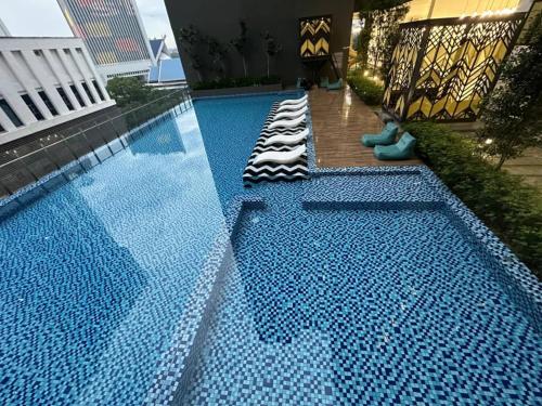 a large swimming pool with chaise lounges next to a building at Alinea suites DSM near by shah alam in Shah Alam