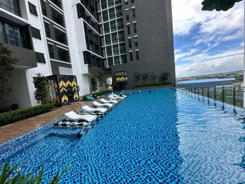 a swimming pool with chaise lounges and chairs on a building at Alinea suites DSM near by shah alam in Shah Alam