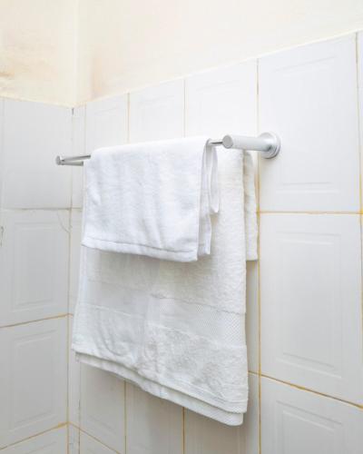 a white towel hanging on a towel rack in a bathroom at Richard's Road Homestay in Boma la Ngombe