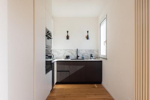 a white kitchen with a sink and a window at Casa Sarina Modern apartment with city and sea view up to 6 ppl garage on request in La Spezia