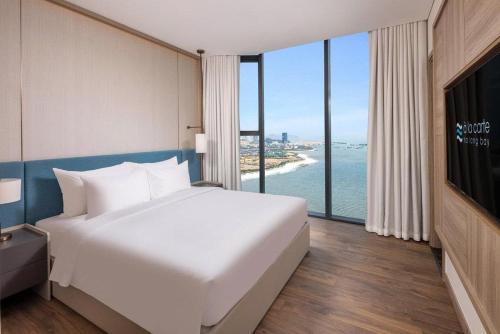 a bedroom with a white bed and a view of the ocean at Alacarte Hạ Long Bích Ngọc in Ha Long