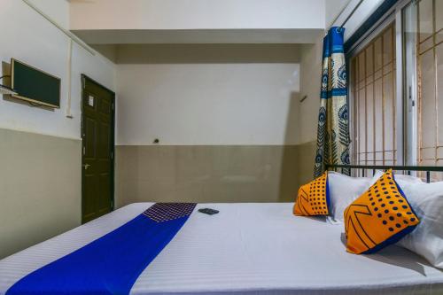 a bedroom with a bed with orange and blue pillows at Hotel O Sai Laxmi in Kolhapur