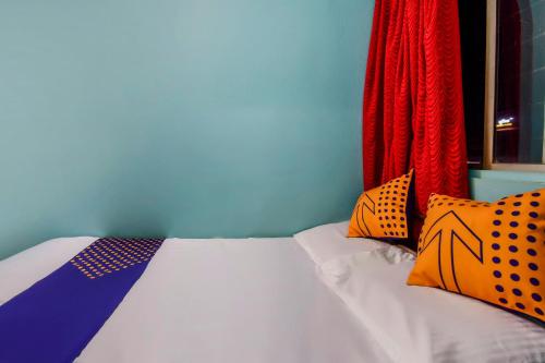 a bed with colorful pillows on it in a room at Hotel O Sai Laxmi in Kolhapur