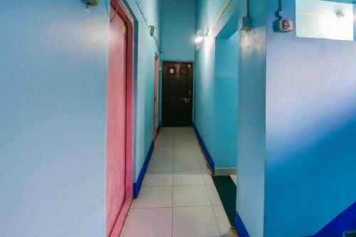 a hallway with blue and pink walls and a door at Hotel O Sai Laxmi in Kolhapur