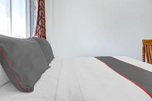 a white bed with a gray pillow and a window at Hotel O Maurya in Pune