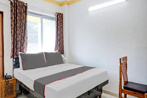 a bedroom with a bed and a window and a chair at Hotel O Maurya in Pune
