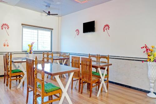 a dining room with tables and chairs and a tv at Hotel O Maurya in Pune