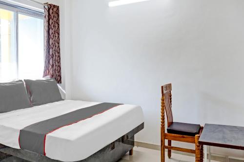 a bedroom with a bed and a desk and a chair at Hotel O Maurya in Pune
