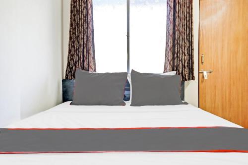 a bed with two pillows and a window at Hotel O Maurya in Pune