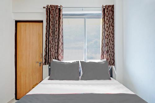 a bedroom with a bed and a window at Hotel O Maurya in Pune