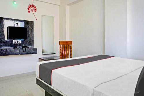 a white bedroom with a bed and a tv at Hotel O Maurya in Pune