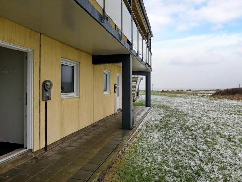 a yellow building next to a field with snow on the ground at 4 person holiday home in Løkken in Løkken