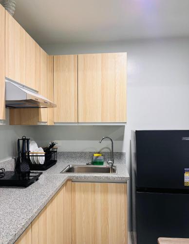 a kitchen with a sink and a black refrigerator at Simple Stylish Retreat with Cozy Touches in Mandurriao