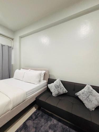 a room with a bed and a couch with pillows at Simple Stylish Retreat with Cozy Touches in Mandurriao