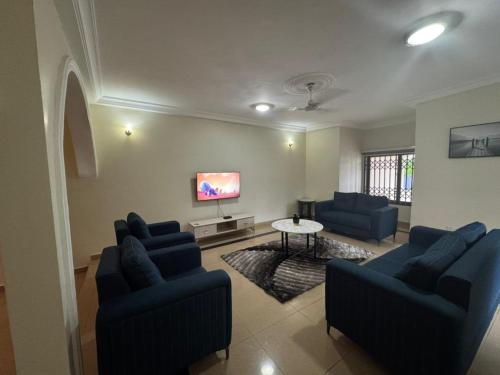 a living room with two blue couches and a tv at Christie's Apartment in Accra
