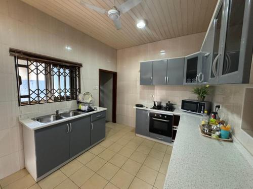 a large kitchen with gray cabinets and a sink at Christie's Apartment in Accra