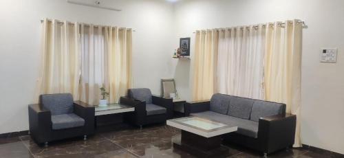 ein Wohnzimmer mit einer Couch und zwei Sesseln in der Unterkunft Footprints Villa in Panchgani