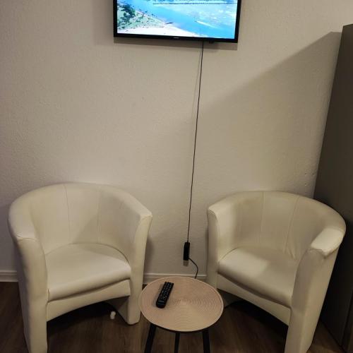 two white chairs and a table and a television at Ferienwohnung 2-Zimmer im Herzen von Osnabrück in Osnabrück