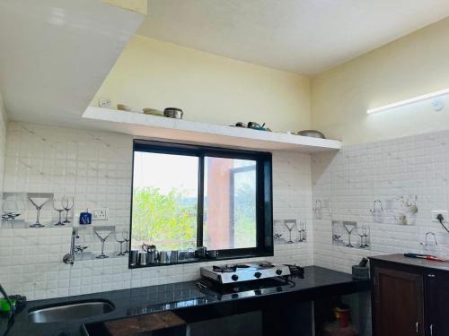 eine Küche mit einem Waschbecken und einem Fenster darin in der Unterkunft Footprints Villa in Panchgani