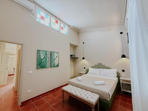 a bedroom with a bed and a bench in it at PalazzoRusso Ortigia Suite & Apartments in Siracusa
