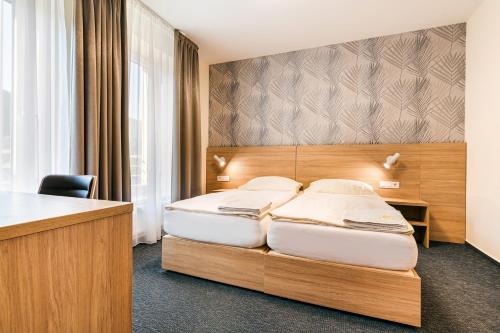 a hotel room with two beds and a desk at Hotel Helios in Lipova Lazne