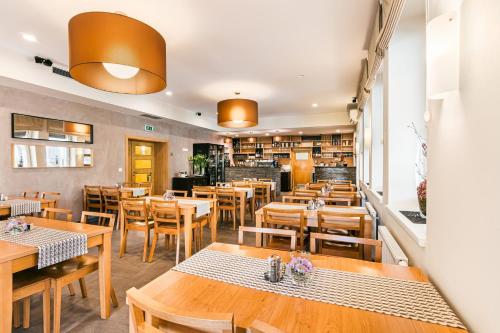 a restaurant with wooden tables and wooden chairs at Hotel Helios in Lipova Lazne