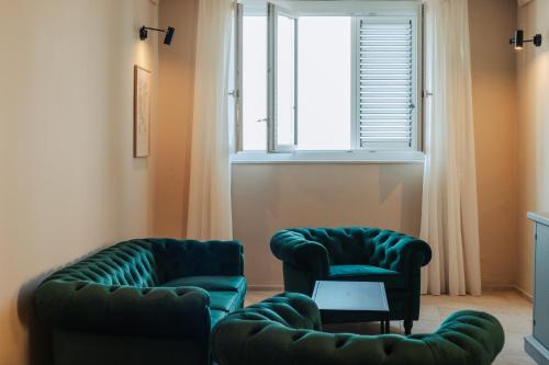 two green chairs in a living room with a window at PalazzoRusso Ortigia Suite & Apartments in Siracusa