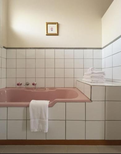 a bathroom with a pink tub and white tiles at Ultimate 70s Charm near Geelong Waterfront and CBD in Bell Post Hill