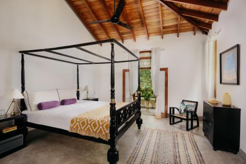 a bedroom with a black canopy bed and a rug at Kalukanda House in Weligama