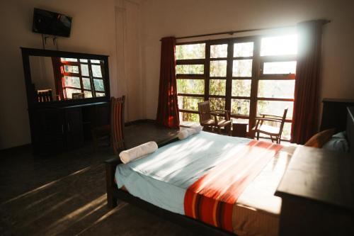 a bedroom with a bed and a table and windows at Rise & Set Arugam bay in Arugam Bay
