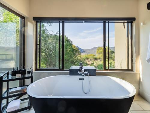 a bath tub in a bathroom with a large window at Shepherds Tree Game Reserve in Pilanesberg
