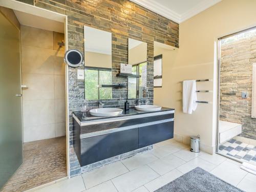 a bathroom with two sinks and a shower at Shepherds Tree Game Reserve in Pilanesberg