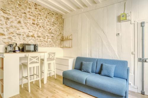 ein Wohnzimmer mit einem blauen Sofa und einem Tisch in der Unterkunft Studio Recollet &Cours - Versailles in Versailles