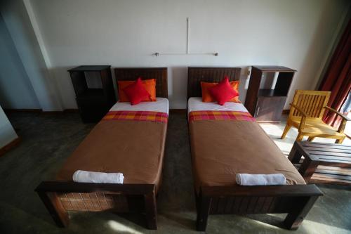 two beds with red pillows in a room at Rise & Set Arugam bay in Arugam Bay