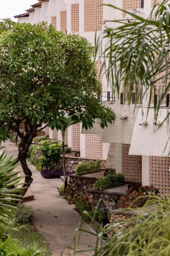 a garden with trees and benches in front of a building at Hotel Tropicana Pattaya in Pattaya