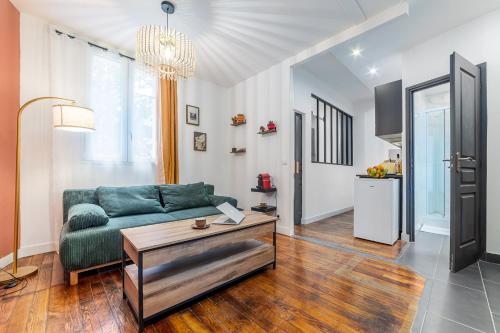 Una sala de estar con un sofá verde y una mesa. en Le Parmentier - RER C à 5min, Self-Checkin, en Vitry-sur-Seine