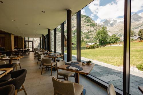a restaurant with tables and chairs with mountains in the background at Grand Hotel Courmayeur Mont Blanc, by R Collection Hotels in Courmayeur